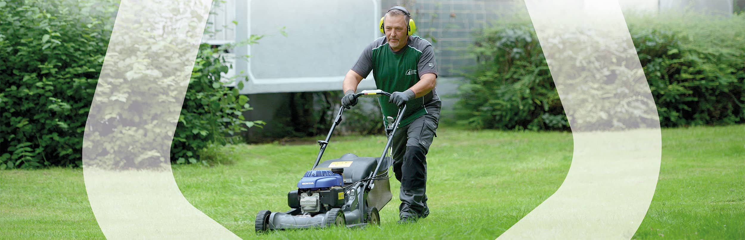 Mitarbeiter mit Rasenmäher bei Gartenpflege